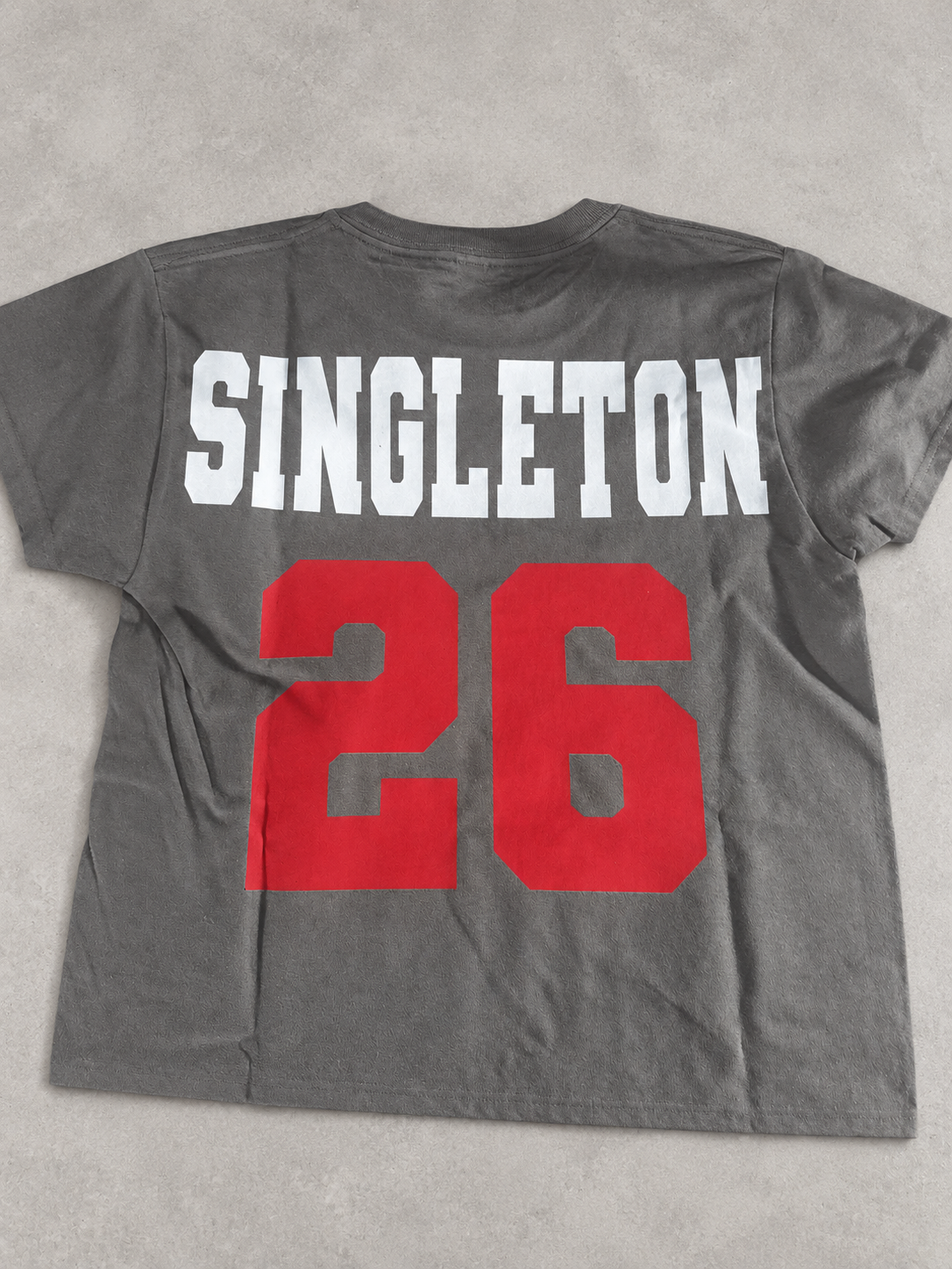 Clean product photo of gray personalized football shirt back with SINGLETON and number 26