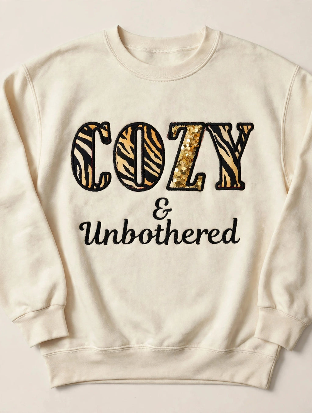 Cozy & Unbothered embroidered sweatshirt - cream sweatshirt with tiger print COZY letters, gold sequin Z, and Unbothered script